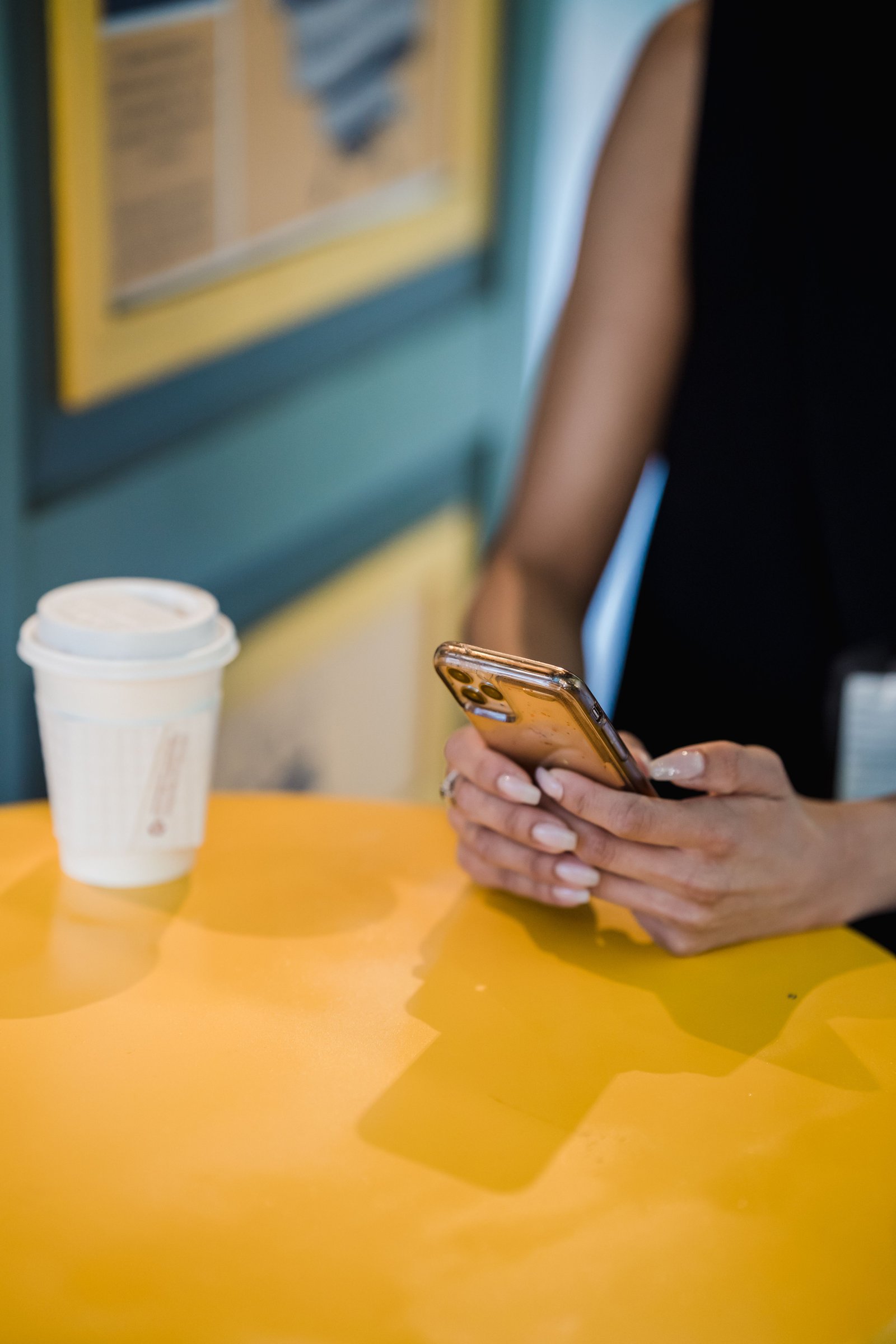 A hand holding a phone showing a loyalty card beside a coffee
