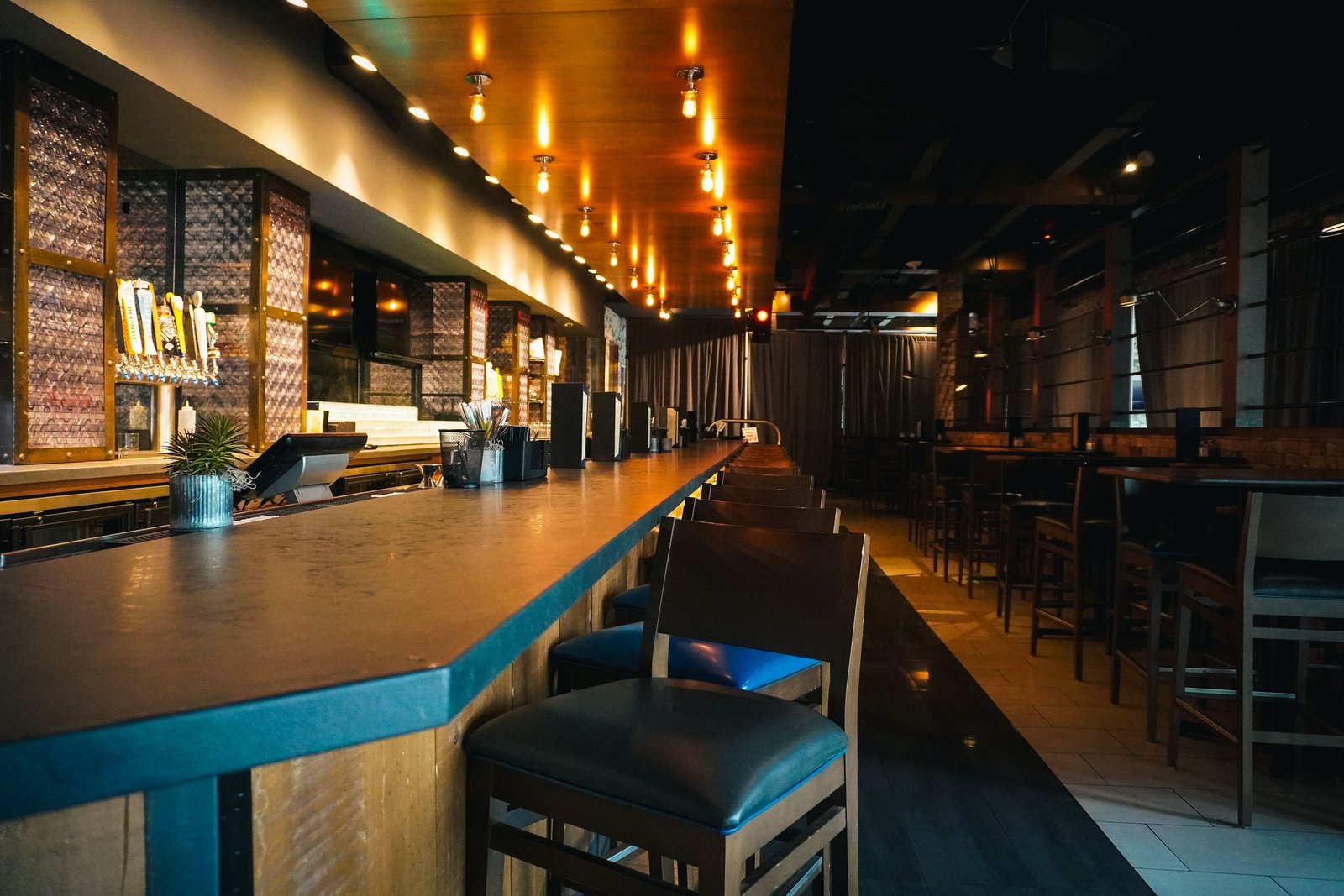 A dimly lit bar with stools and warm lights